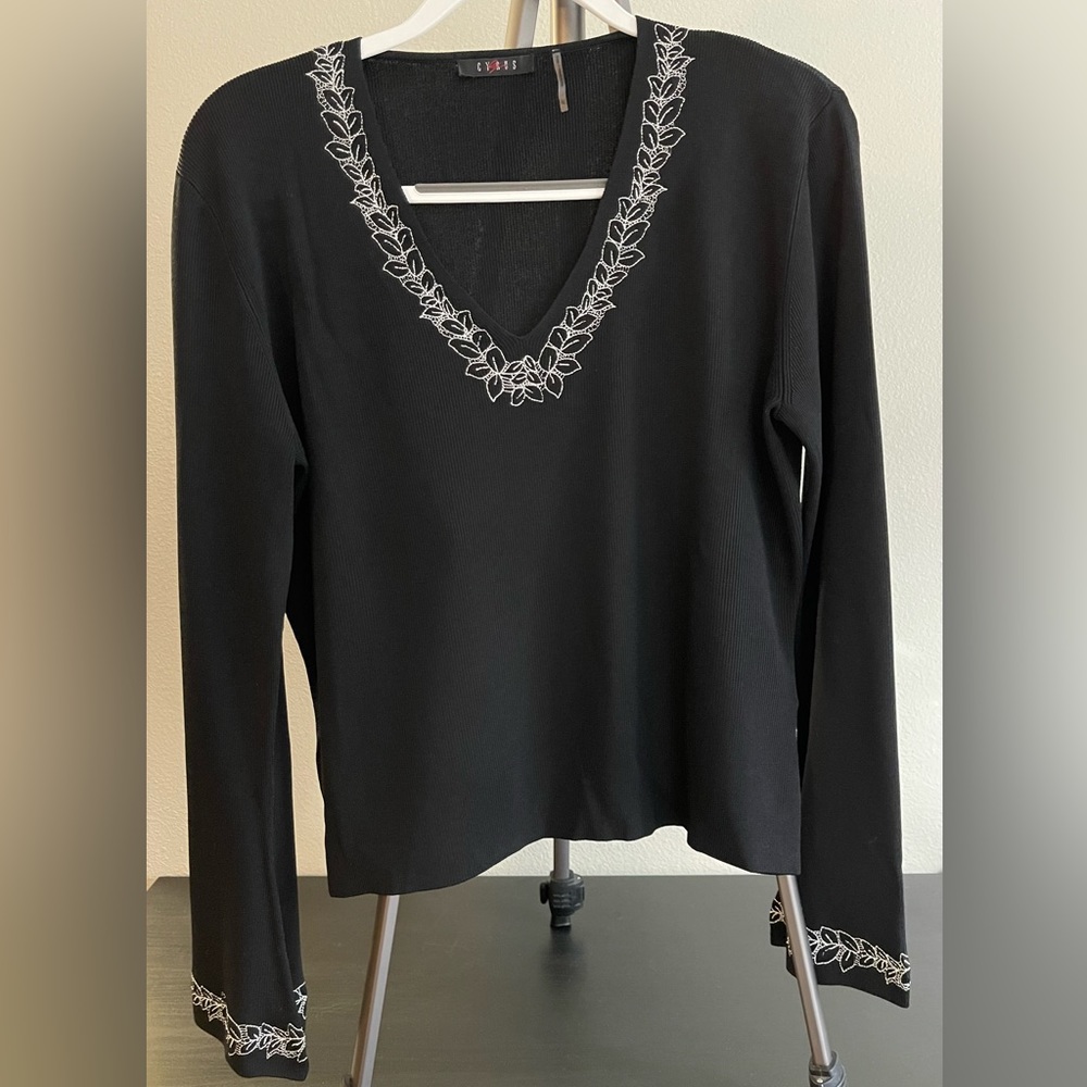 Women’s black sweater with white design at neckline and cuffs.